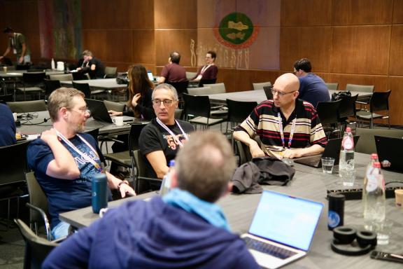 People working at laptops around tables in the contribution room at DrupalCon Rotterdam 2026.