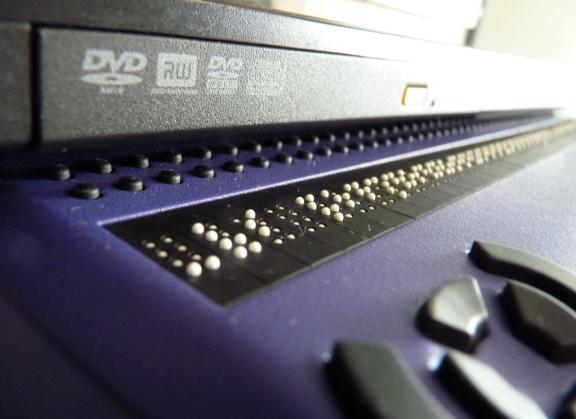 Close-up of a refreshable braille display, its raised pins set into a blue keyboard unit.