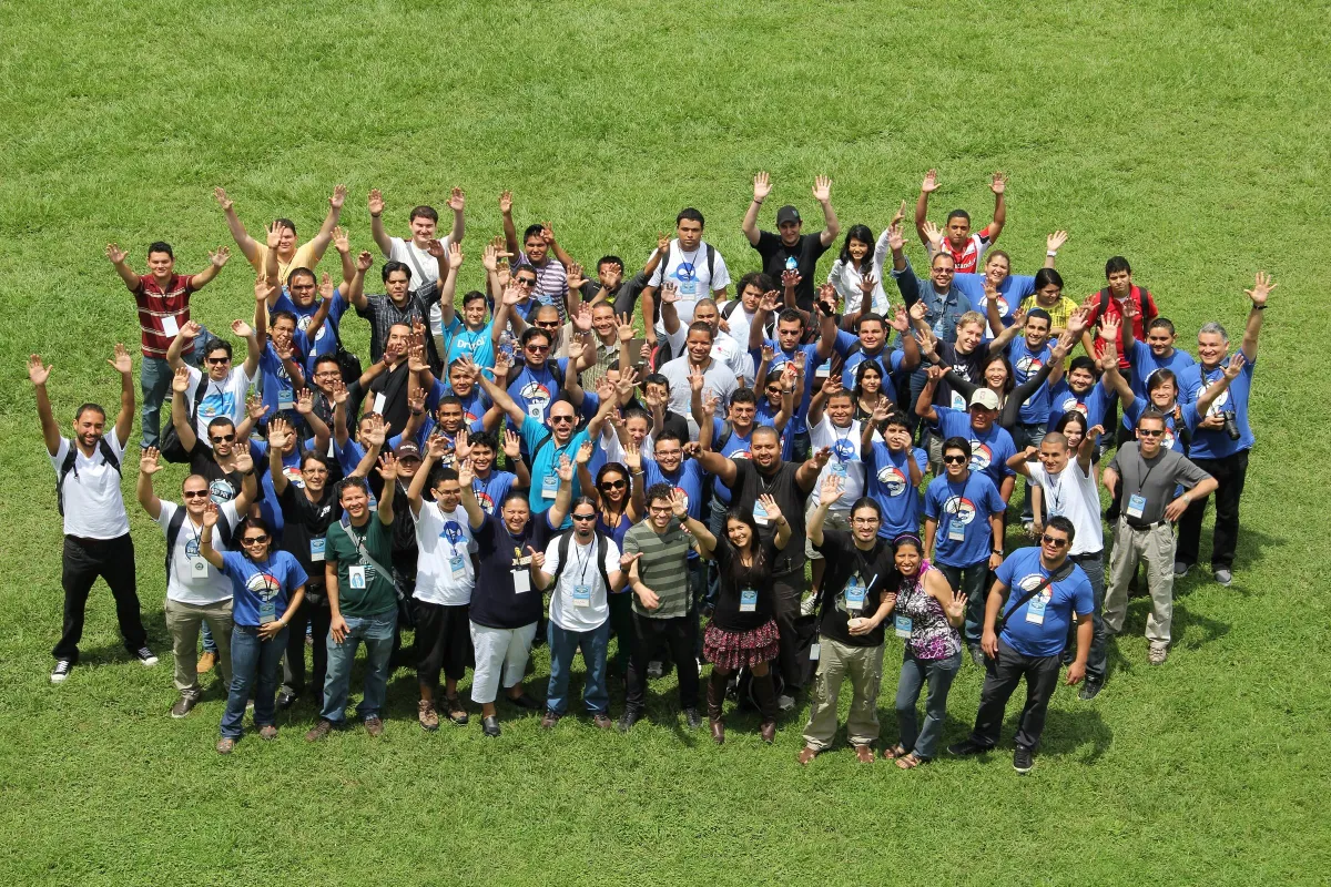 A large group of DrupalCamp Centroamérica attendees waving at the camera on a lawn