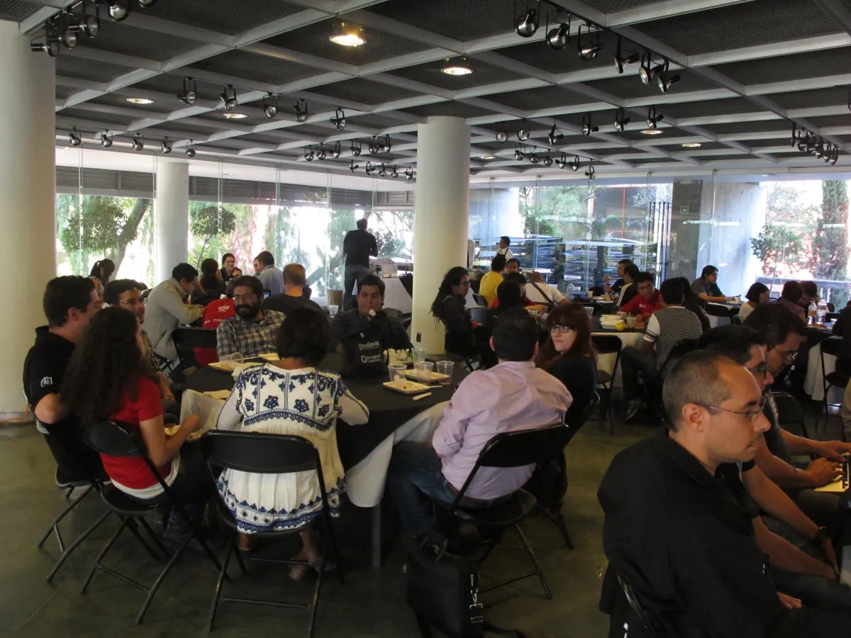 People talking over lunch at round tables at DrupalCamp México