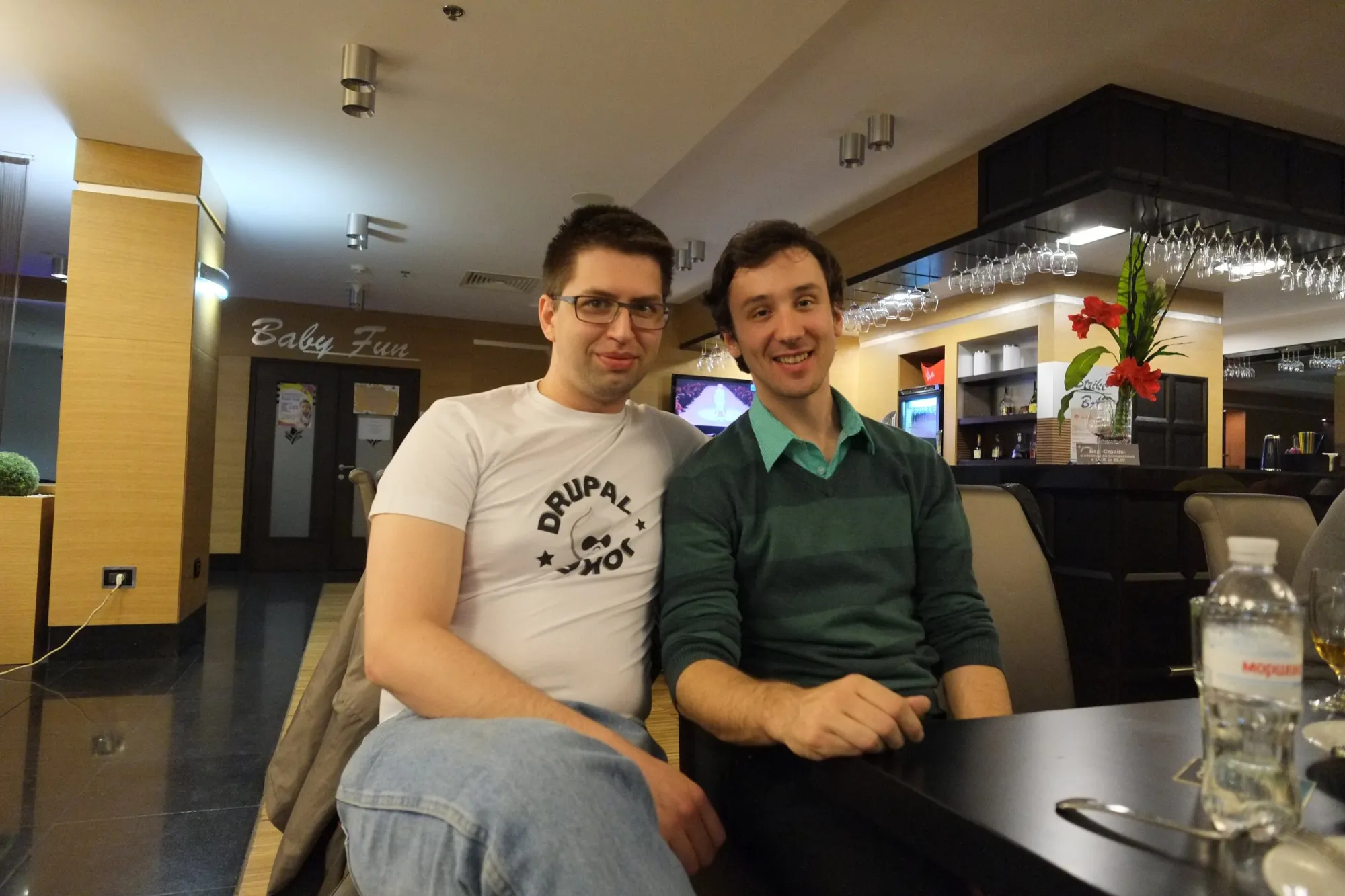 Two Drupal developers smiling at a café table during DrupalCamp Donetsk