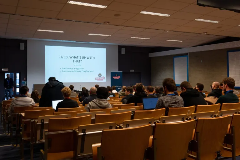 Developers in a lecture room watching a talk about continuous integration at Drupal Dev Days Ghent 2022.