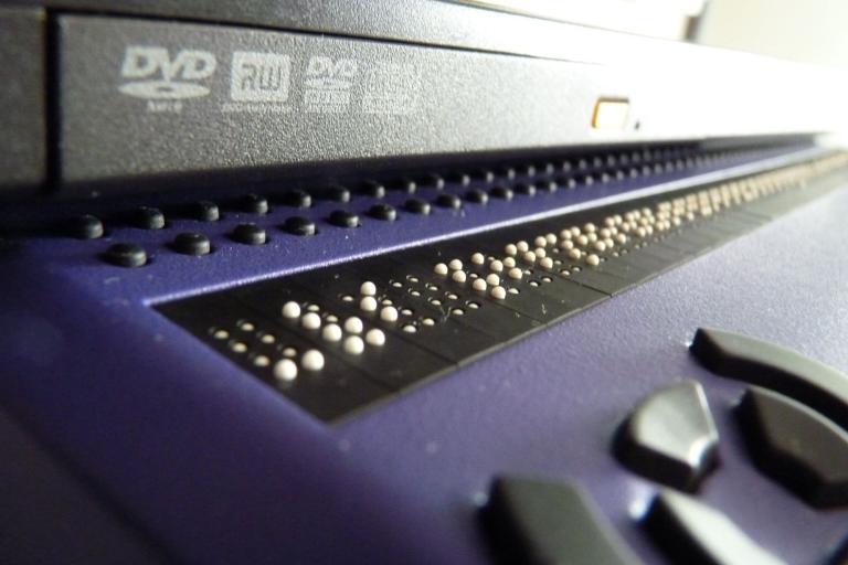 Close-up of a refreshable braille display, its raised pins set into a blue keyboard unit.
